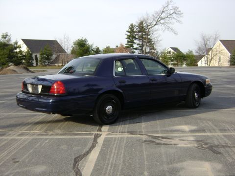 2001 Ford Crown Victoria - A dark blue 2001 Ford Crown Victoria sedan is seen from the rear quarter angle in a parking lot.