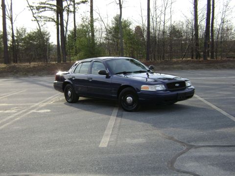 2001 Ford Crown Victoria - This sedan is parked in an empty lot with a line of trees visible behind it.