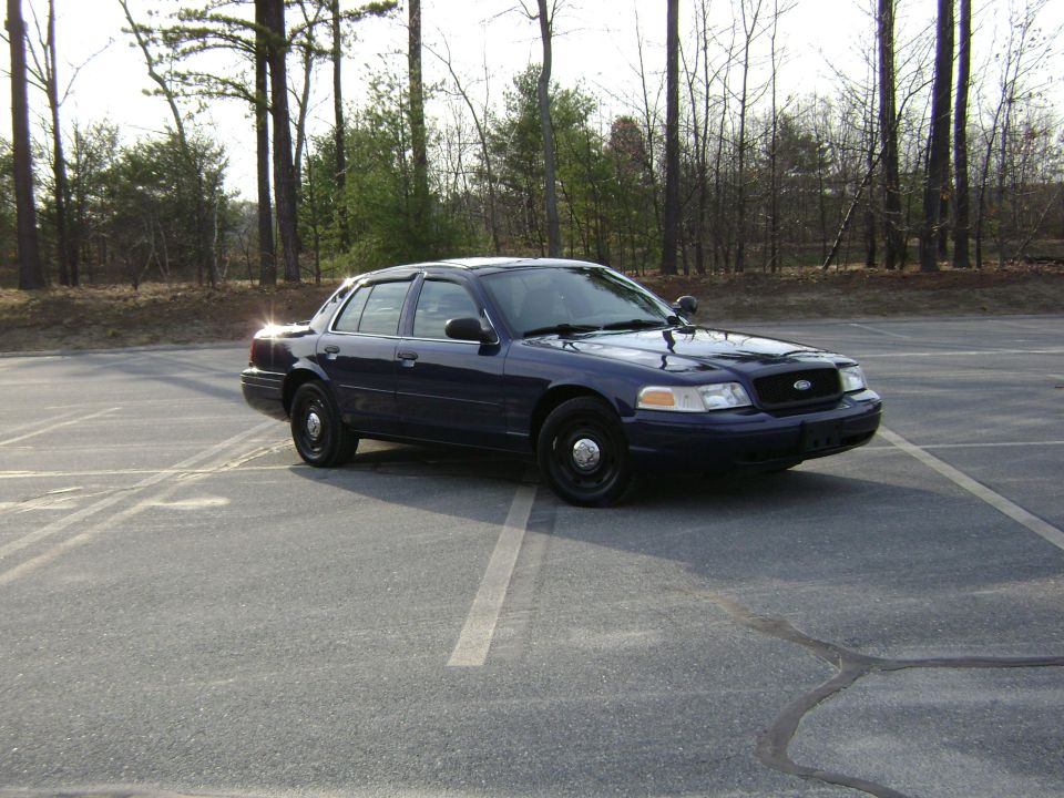 Dark blue 2001 Ford Crown Victoria parked in a lot with trees in the background