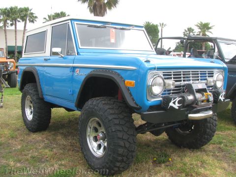 1968 Ford Mustang - A lifted blue 1973 Ford Bronco is parked on grass with palm trees in the background.