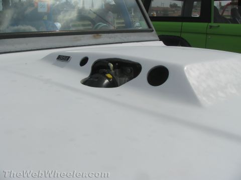1968 Ford Mustang - Close-up of a white car's hood a scoop and '351' badging, with another vehicle in the background.