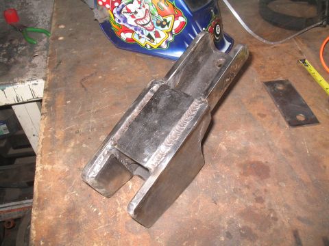 1979 Ford Bronco - A custom-welded metal component rests on a workbench, alongside a welding helmet and measuring tape.