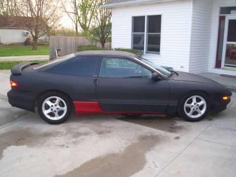 1993 Ford Probe - Side view of a black coupe with red lower body panels and a rear spoiler.