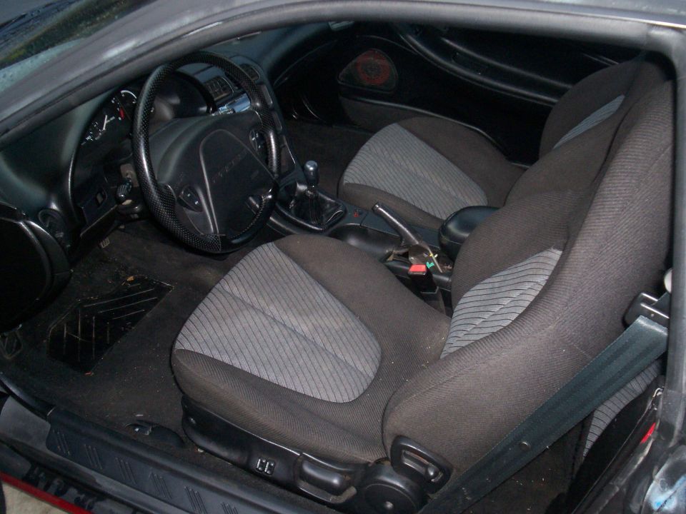 Gray cloth interior of a coupe with manual shifter and steering wheel