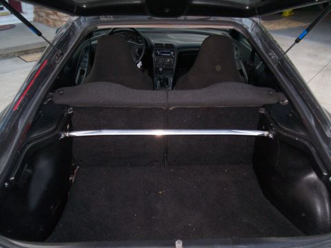 1993 Ford Probe - The trunk of a car is open, revealing the interior and a chrome strut bar across the cargo area.