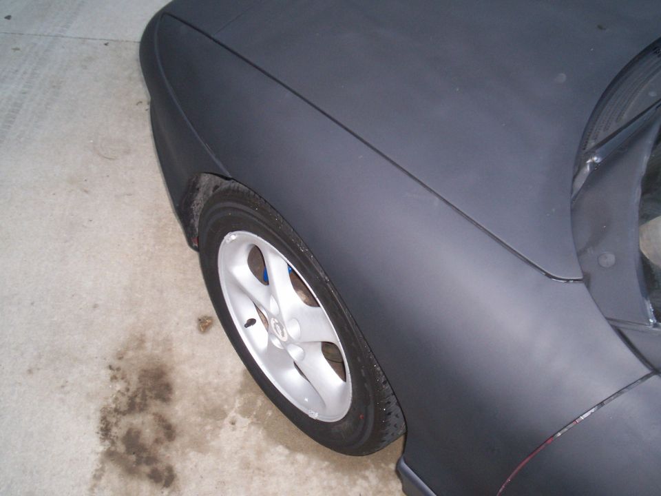 Car's front fender and wheel, matte black paint, silver 5-spoke rim