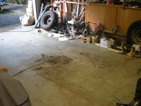 1993 Ford Bronco - A cluttered garage scene displays various vehicle components strewn across the concrete floor.