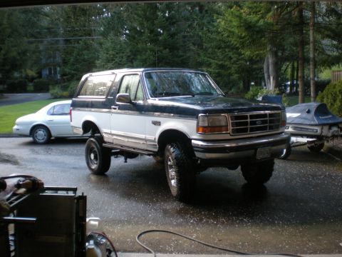 1993 Ford Bronco - A two-tone Ford Bronco with aftermarket wheels and tires is parked outside.