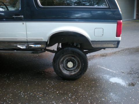 1993 Ford Bronco - The rear side profile of a 1993 Ford Bronco, showing its two-tone paint scheme and lifted suspension.
