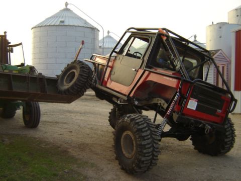 1992 Ford Bronco - A heavily modified off-road vehicle is being loaded onto a trailer by a forklift.