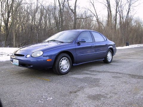 1996 Ford Taurus - A blue 1996 Ford Taurus sedan is viewed from the front three-quarter angle on a paved surface.