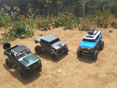 1988 Ford Bronco - A green 1988 Ford Bronco RC vehicle is parked on a dirt path with two other RC vehicles.