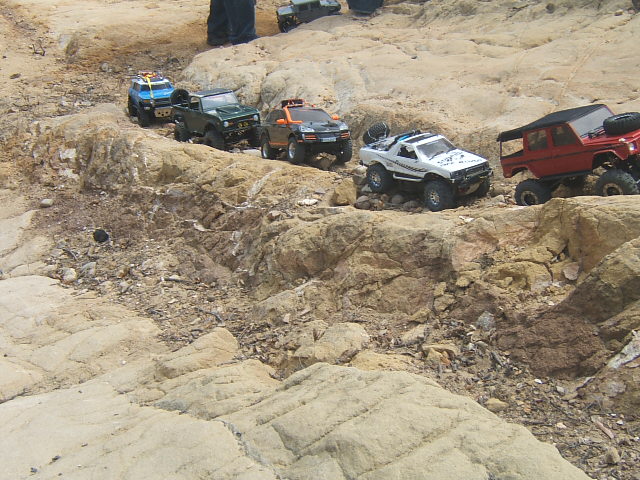 Several remote control trucks driving over rocks