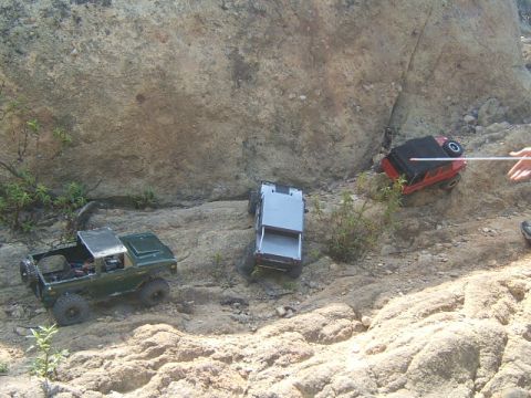 1988 Ford Bronco - RC vehicles tackle a challenging rocky incline, with one vehicle on its side.