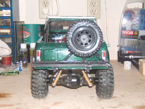 1988 Ford Bronco - Rear view of a green 1988 Ford Bronco RC crawler model with a spare tire on the back.