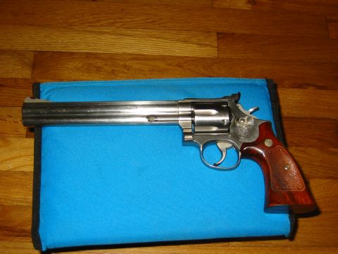 1996 Ford Bronco - A revolver handgun with wooden grips rests on a blue case against a wooden background.