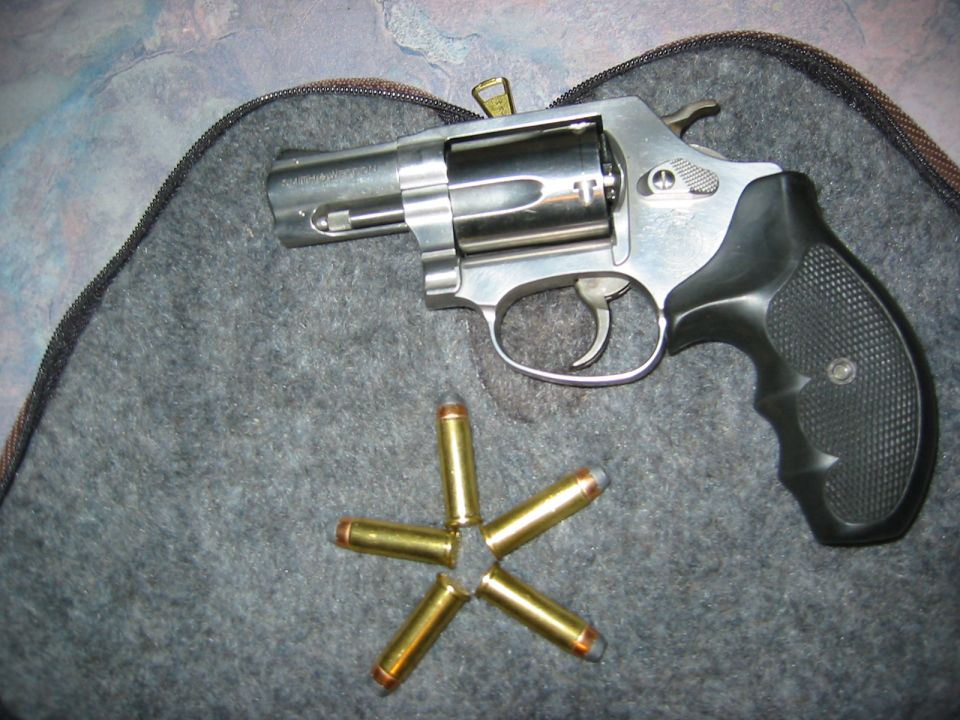 revolver with five cartridges arranged in a star pattern on a gray fabric surface