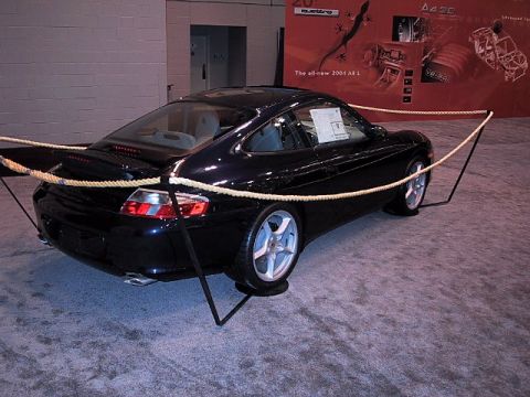 1996 Ford Taurus - A black Porsche 911 is displayed at an auto show, with signage in the background mentioning the 'all-new 2004 A8 L'.