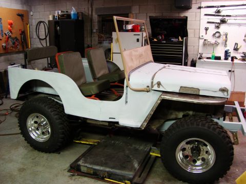 1948 Jeep Wrangler - A 1948 Jeep Wrangler body is shown in a garage, appearing to be in the process of restoration or awaiting bodywork and restoration.