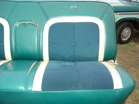 1979 Ford F-150 - The interior of a 1979 Ford F-150 shows a green and white bench seat, with the exterior of another vehicle visible to the right.