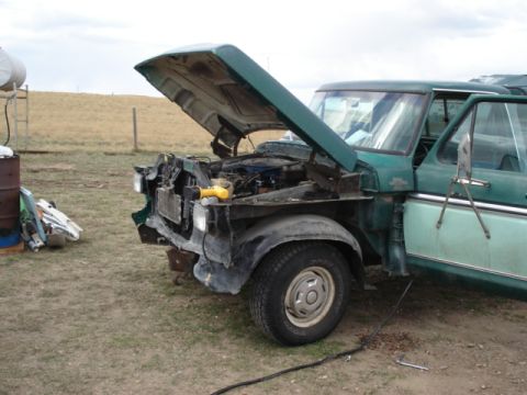 1979 Ford F-150 - A green 1979 Ford F-150 pickup truck sits outdoors with its hood open, revealing the engine compartment and some front-end damage.