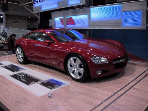 1996 Ford Taurus - A red coupe concept car is displayed at an auto show.