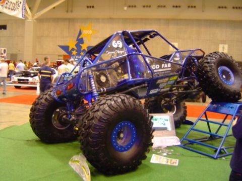 1979 Ford Bronco - A custom-built buggy with a blue frame and massive tires is displayed indoors.