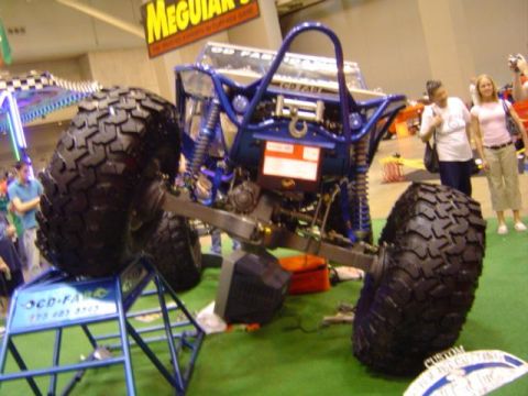1979 Ford Bronco - A heavily modified off-road vehicle is displayed indoors with large tires and a custom blue roll cage.
