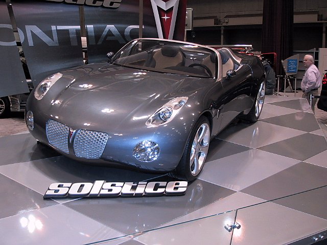 Gray Pontiac Solstice concept car on display floor with 'SOLSTICE' badge