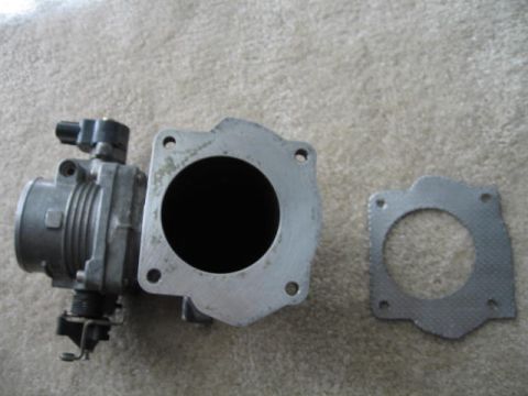 1995 Mercury Cougar - A throttle body assembly and its corresponding gasket are shown, likely for automotive repair or replacement.