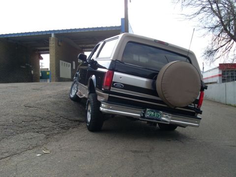1996 Ford Bronco - A 1996 Ford Bronco is parked on an incline in front of a car wash structure.