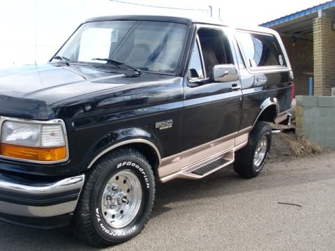 1996 Ford Bronco - A clean black and tan Ford Bronco is parked outside a building.