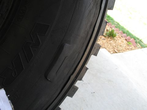 1995 Ford Bronco - A close-up view of a tire's sidewall reveals damage and some embossed lettering.