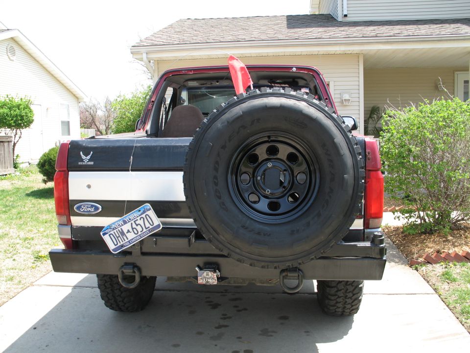 Rear of red and silver Ford SUV with tube bumper and swing-out Goodyear Wrangler spare