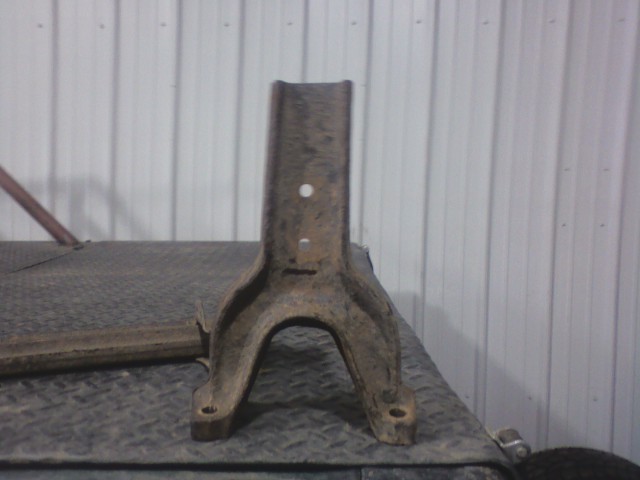 Rusty metal automotive part with two mounting holes at the base and a single hole near the top