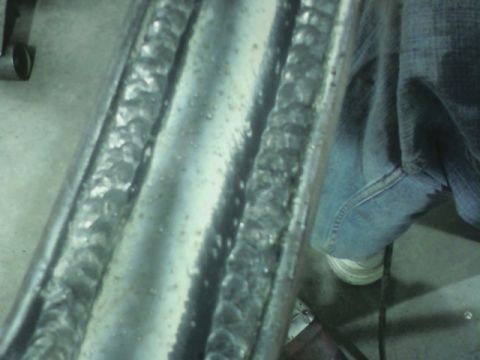 1992 Ford F-350 - This photo shows a close-up view of metal welds on a frame, with a person's leg and shoe in the background.