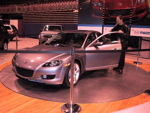 1996 Ford Taurus - Mazda RX-8 displayed at an auto show, with a Ford Explorer in the background.