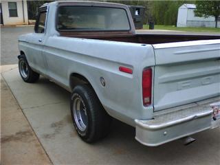 1995 Ford Bronco - Rear view of a 1975 Ford F-100 pickup truck with a chrome bumper and light blue paint.