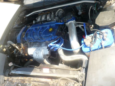 1993 Ford Probe - Close-up view of a modified engine bay, custom blue components and a large intake pipe.