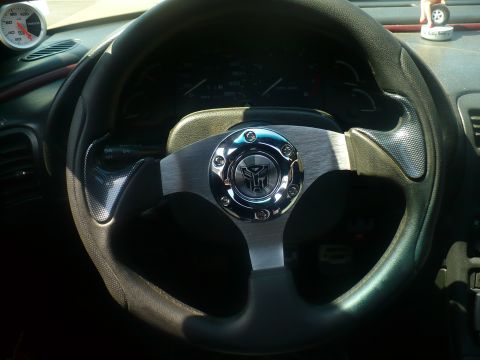 1993 Ford Probe - Interior view of a steering wheel with a Transformers emblem and an aftermarket gauge.