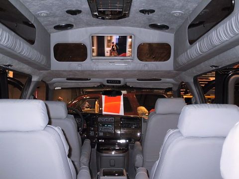 1996 Ford Taurus - The interior of a customized van features multiple rows of seating and an overhead entertainment system.