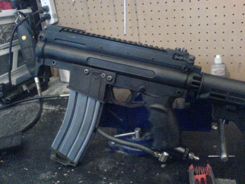 1985 Ford Bronco - A black rifle with a loaded magazine and an air hose is secured in a vise on a workbench.