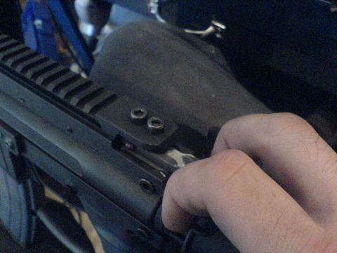 1985 Ford Bronco - Close-up of a firearm receiver with a Picatinny rail and a hand manipulating the charging handle.