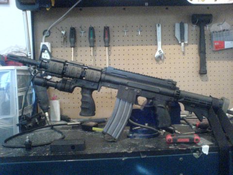 1985 Ford Bronco - Modified assault rifle with tactical accessories displayed on a cluttered workbench.