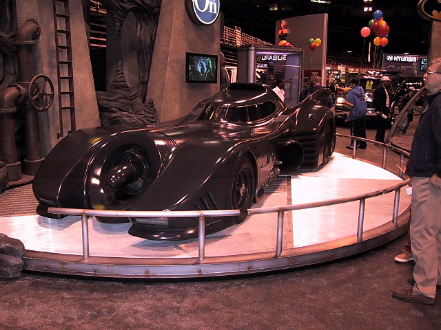 Black Batmobile on display platform, front three-quarter view
