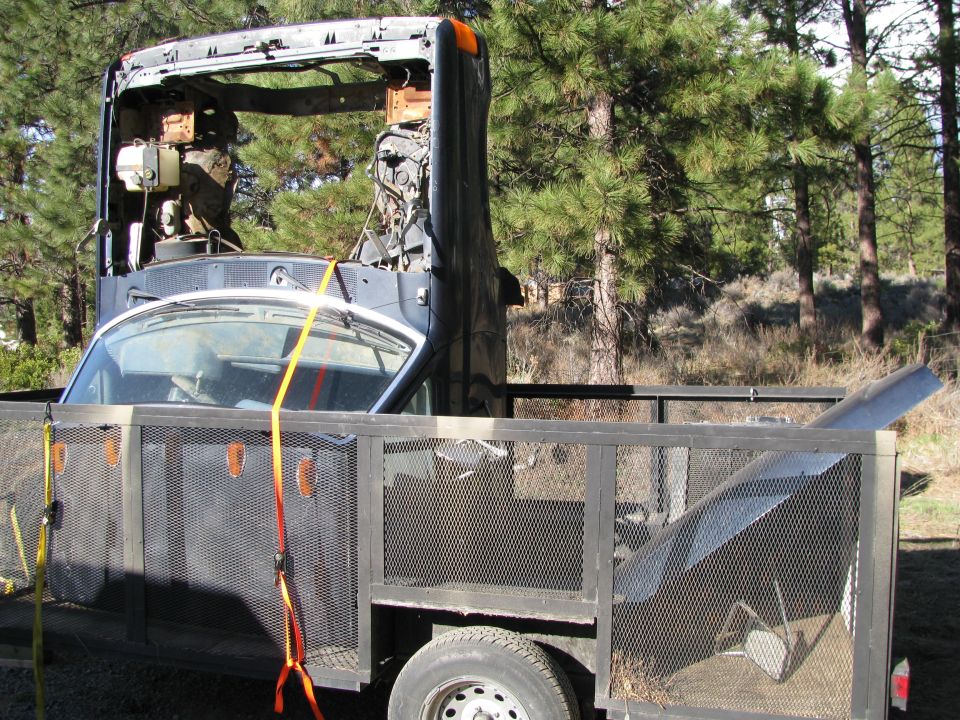 Cab windshield frame and parts strapped on a utility trailer