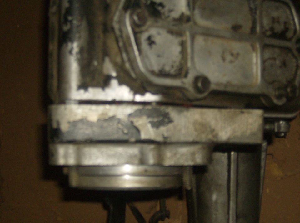 Close-up of a metal engine component with peeling paint and visible bolts