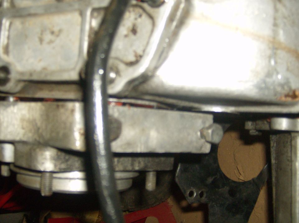 Close-up of a vehicle's transmission housing with a black hose running across it