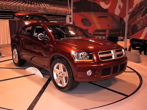 1996 Ford Taurus - A red SUV with a distinctive chrome grille and pop-up headlights is showcased at an auto show.