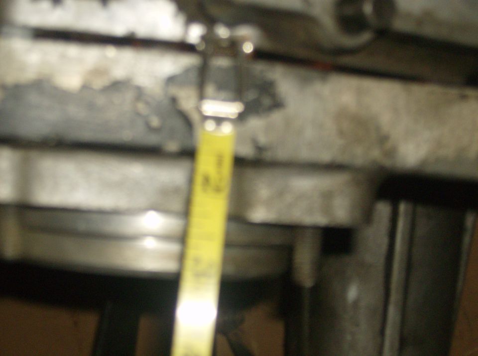 Engine part with yellow measuring tape showing inches